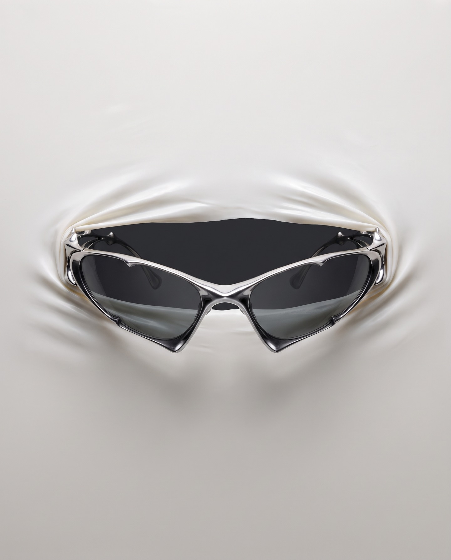 Sculptural silver sunglasses emerging through pearl-white latex